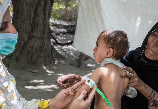 Klimatkrisen - en mormor på besök på en hälsoklinik håller sitt barnbarn medans han undersöks för undernäring.